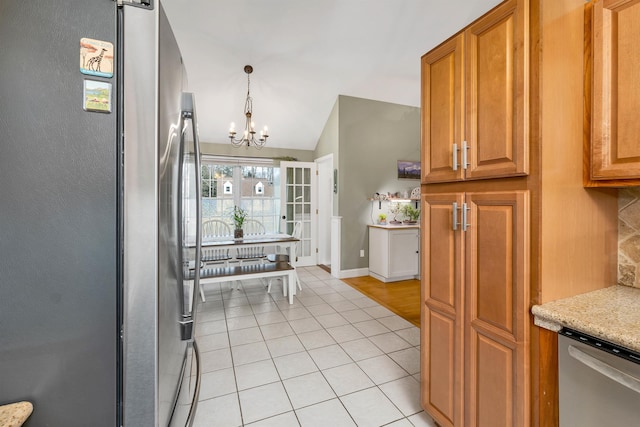 kitchen featuring light tile patterned floors, appliances with stainless steel finishes, brown cabinets, and a chandelier