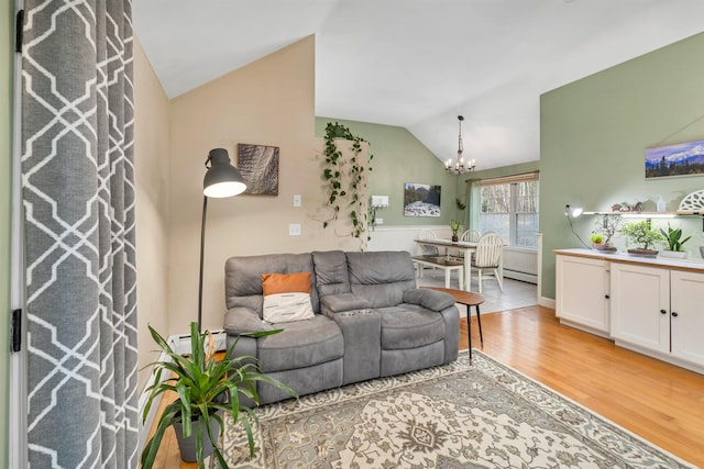 living room featuring lofted ceiling, light wood finished floors, and an inviting chandelier