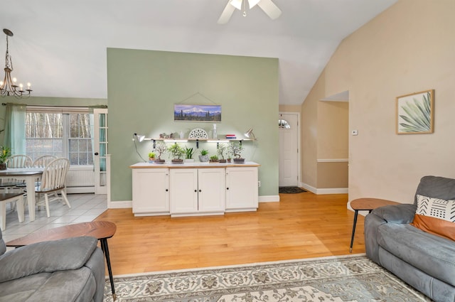 living room with lofted ceiling, a baseboard radiator, baseboards, and light wood-style floors