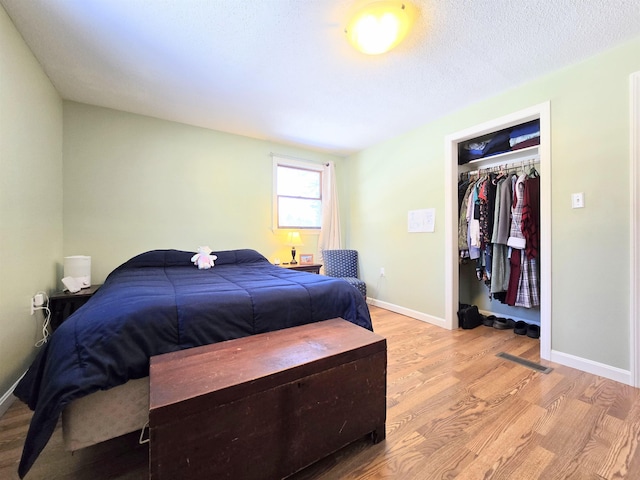 bedroom with visible vents, a textured ceiling, light wood-style flooring, and baseboards