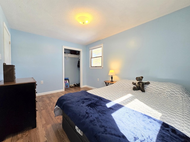 bedroom with a textured ceiling, a closet, baseboards, and wood finished floors