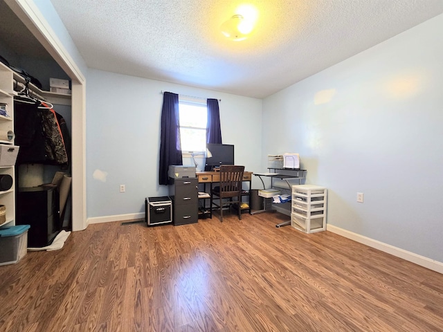 office area featuring a textured ceiling, baseboards, and wood finished floors