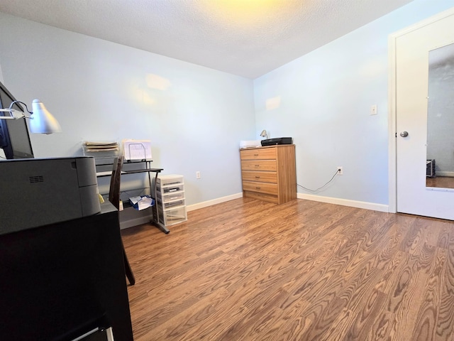 office area with a textured ceiling, baseboards, and wood finished floors