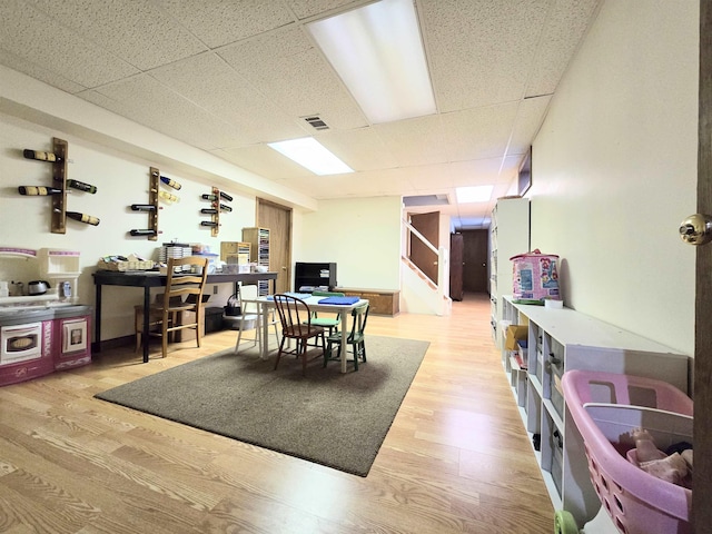 dining space with light wood finished floors, stairway, visible vents, and a drop ceiling