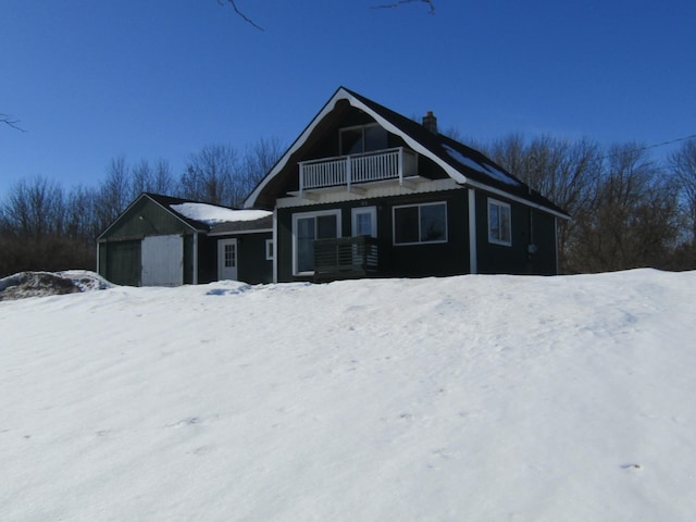 view of front of home with a chimney, a detached garage, and a balcony