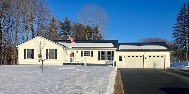 ranch-style house featuring metal roof, driveway, a standing seam roof, and an attached garage