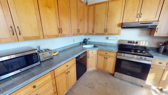 kitchen featuring light tile patterned floors, tile counters, stainless steel appliances, under cabinet range hood, and a sink