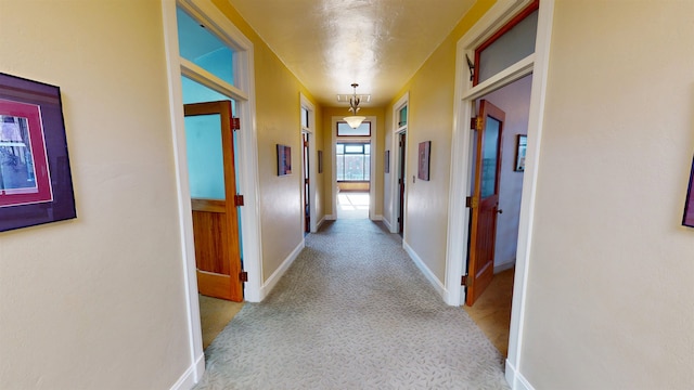 hallway with carpet, visible vents, and baseboards