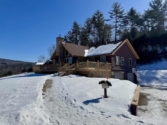 view of front of property with a garage, a chimney, and a wooden deck