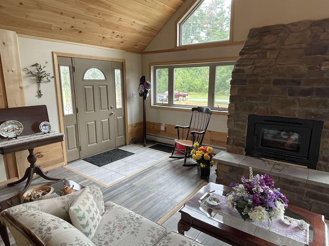 foyer featuring light wood-style flooring, wooden ceiling, vaulted ceiling, and a stone fireplace