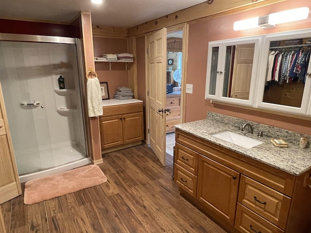 full bath with a stall shower, vanity, and wood finished floors