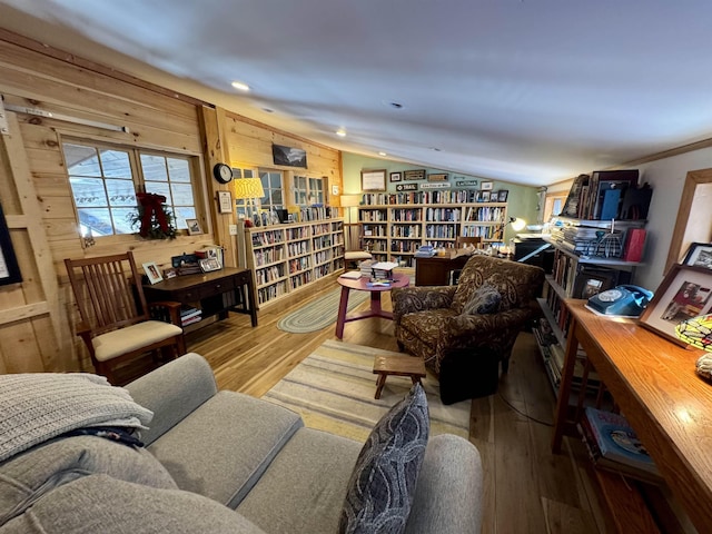 living area with lofted ceiling, wall of books, wood finished floors, and recessed lighting