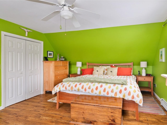 bedroom with baseboards, ceiling fan, wood finished floors, vaulted ceiling, and a closet