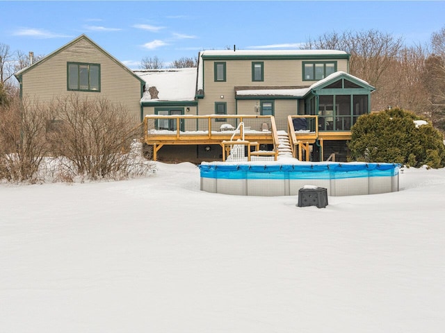 snow covered property featuring a sunroom, a covered pool, and a wooden deck