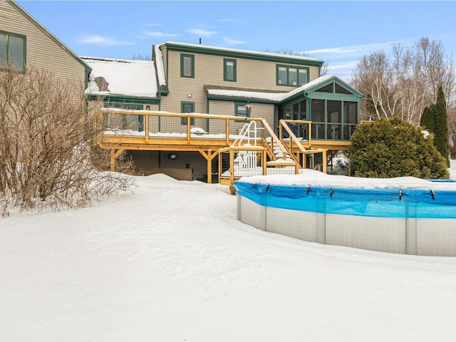 snow covered pool featuring a sunroom, a covered pool, and a wooden deck