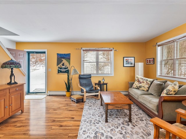 living room with a healthy amount of sunlight, light wood finished floors, and a baseboard heating unit