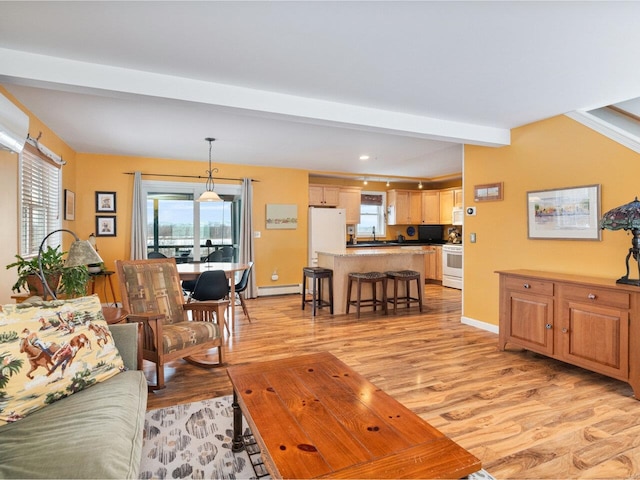 living room with a baseboard heating unit, light wood finished floors, beamed ceiling, and baseboards