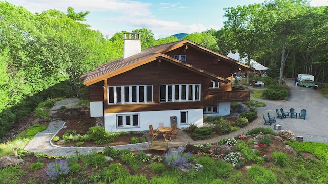 back of property with a chimney and a patio