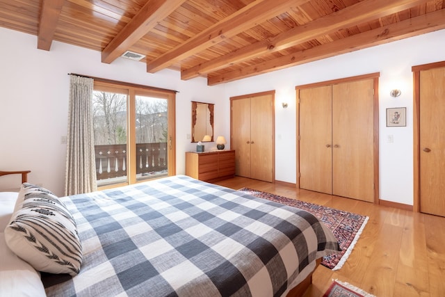 bedroom with two closets, visible vents, light wood-style floors, wooden ceiling, and baseboards