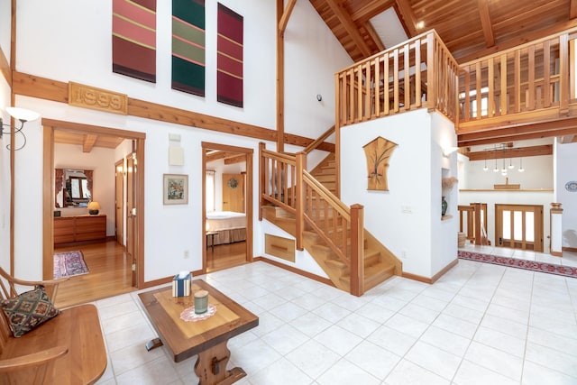 living room with high vaulted ceiling, beamed ceiling, tile patterned flooring, and baseboards