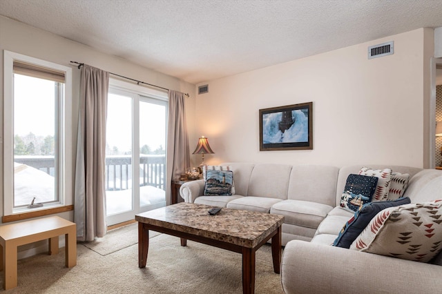 living area featuring light carpet, visible vents, and a textured ceiling