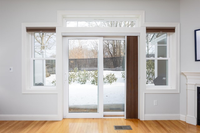 entryway featuring light wood-style floors, baseboards, a fireplace, and visible vents