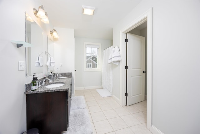 bathroom with double vanity, tile patterned flooring, baseboards, and a sink