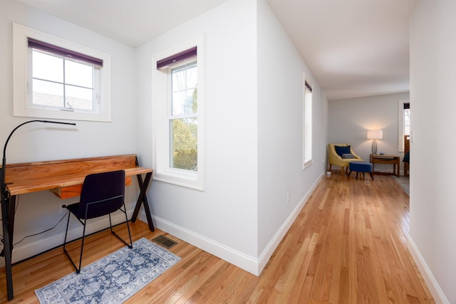 office area with light wood finished floors, visible vents, and baseboards