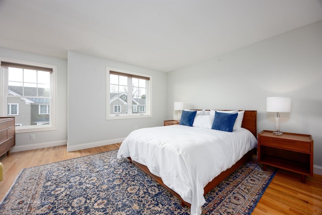 bedroom with multiple windows, baseboards, and wood finished floors