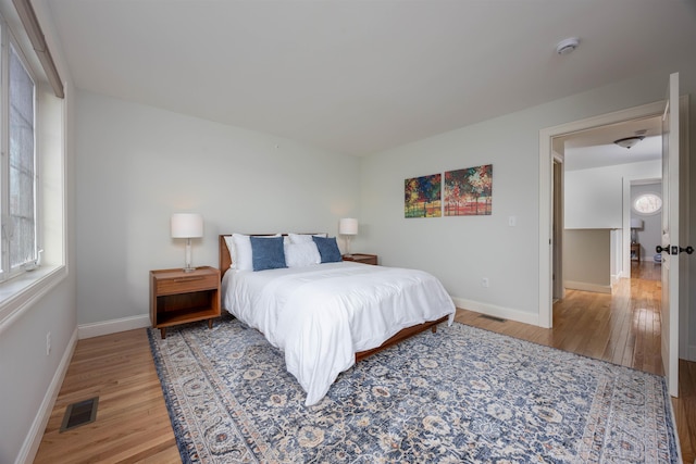 bedroom with wood finished floors, visible vents, and baseboards