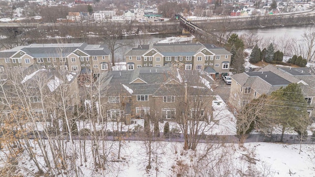 snowy aerial view featuring a water view and a residential view