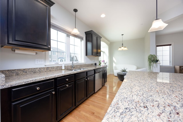 kitchen featuring light wood-type flooring, a sink, dishwasher, and hanging light fixtures