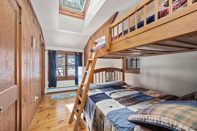 bedroom featuring a skylight, hardwood / wood-style floors, and a baseboard radiator