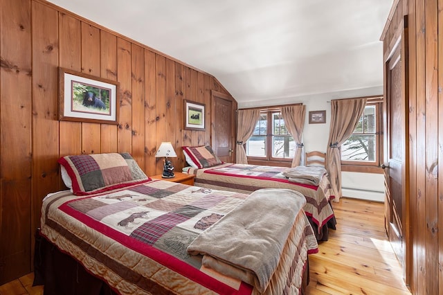 bedroom featuring light wood-type flooring, wood walls, lofted ceiling, and a baseboard radiator