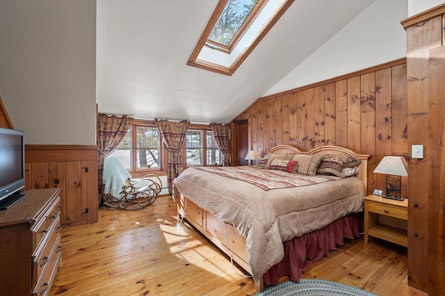 bedroom featuring lofted ceiling with skylight, wooden walls, and light wood finished floors