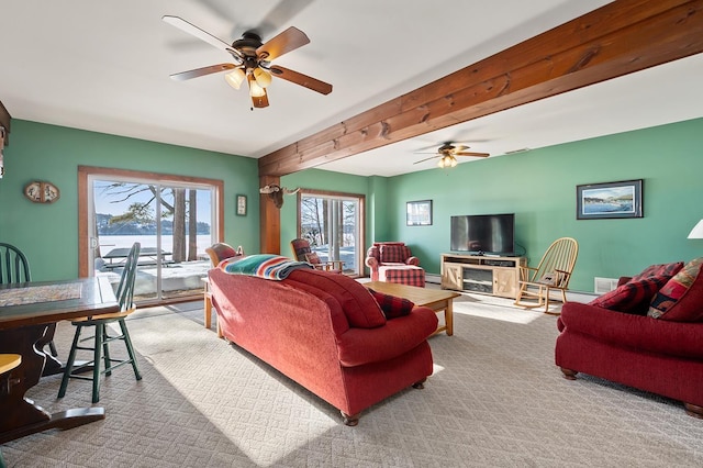 carpeted living area with a ceiling fan and beam ceiling