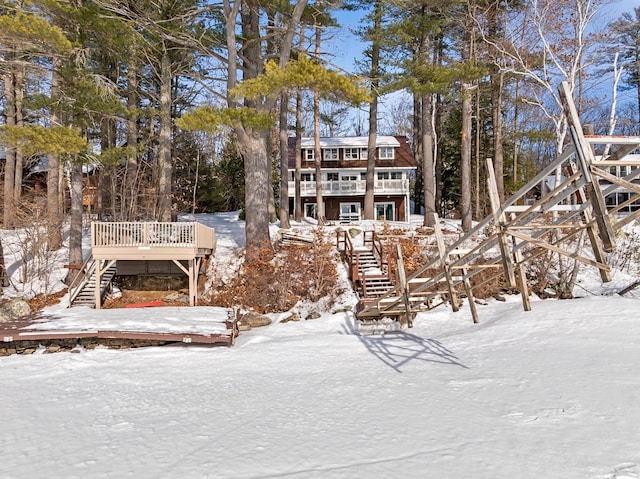 snow covered house featuring stairway and a wooden deck