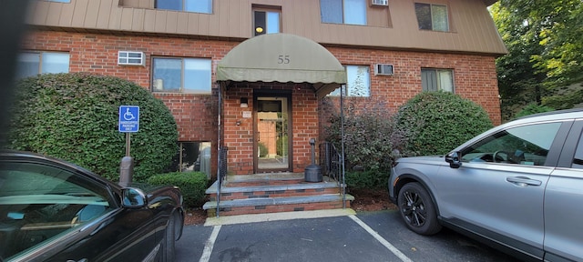 entrance to property featuring uncovered parking and brick siding