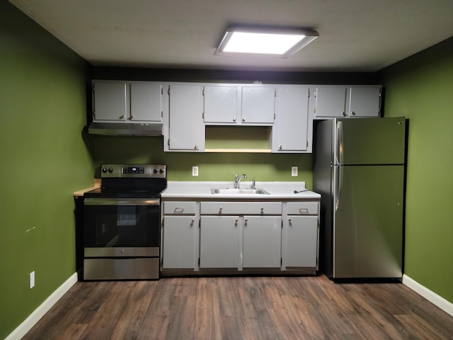 kitchen with under cabinet range hood, a sink, baseboards, appliances with stainless steel finishes, and dark wood-style floors