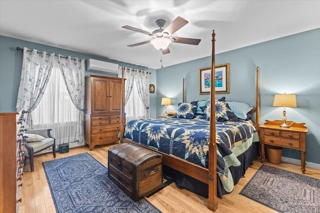 bedroom with light wood-style floors, ceiling fan, baseboards, and a wall mounted AC