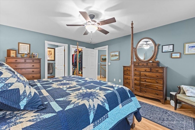 bedroom with connected bathroom, a ceiling fan, wood finished floors, a walk in closet, and a closet