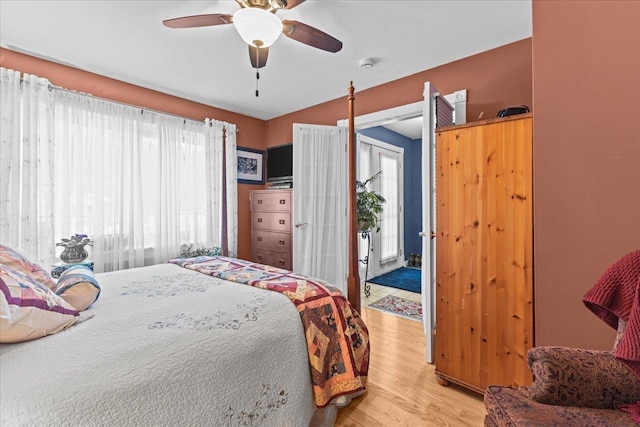 bedroom featuring access to exterior, light wood-style flooring, and a ceiling fan