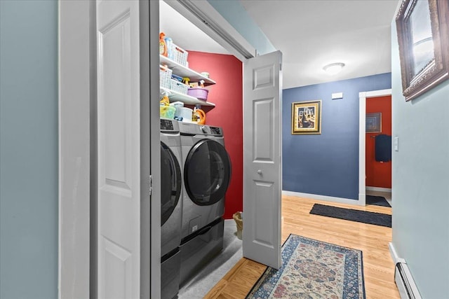 laundry room featuring light wood finished floors, laundry area, baseboards, a baseboard radiator, and washing machine and clothes dryer