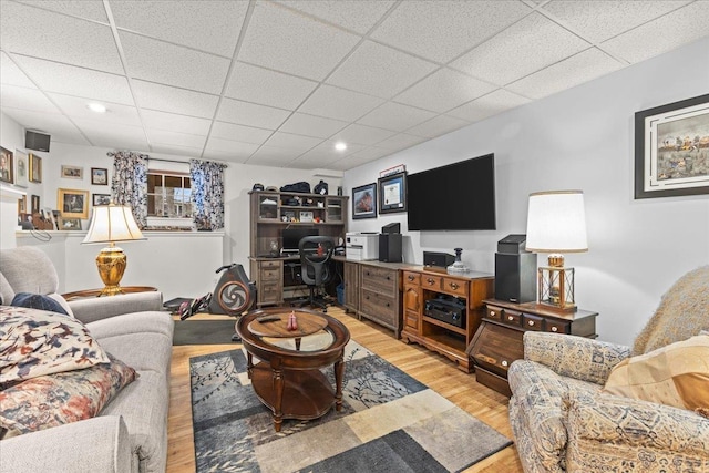 living room featuring a drop ceiling, light wood-style flooring, and recessed lighting