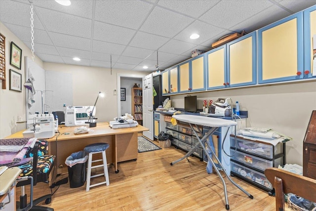 office space featuring light wood finished floors, a drop ceiling, and recessed lighting