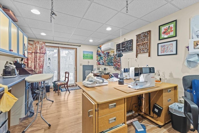 office space with a wall unit AC, light wood-type flooring, a paneled ceiling, and recessed lighting