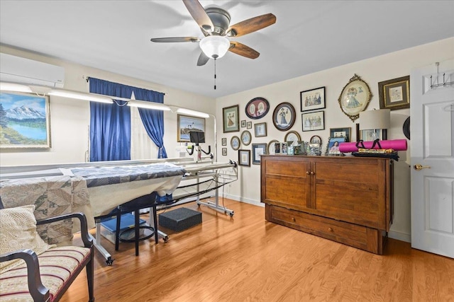 misc room featuring ceiling fan, a wall unit AC, wood finished floors, and baseboards