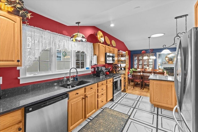 kitchen featuring appliances with stainless steel finishes, a sink, vaulted ceiling, pendant lighting, and a notable chandelier