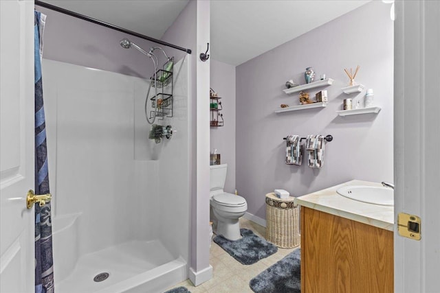 full bathroom featuring vanity, a shower stall, toilet, and baseboards