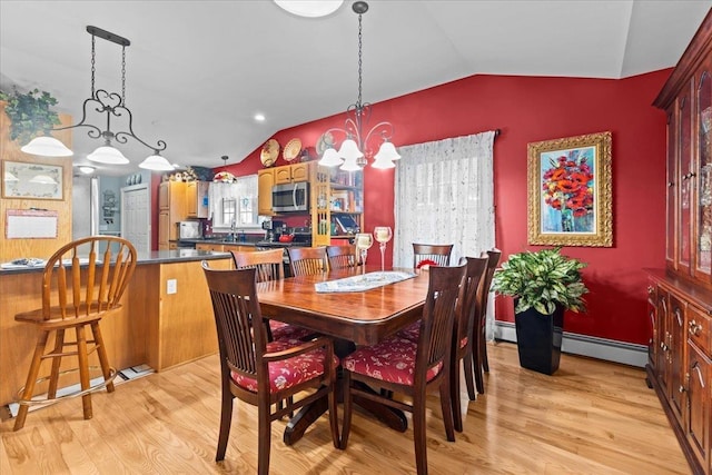 dining area with lofted ceiling, light wood-style flooring, a baseboard heating unit, and a notable chandelier